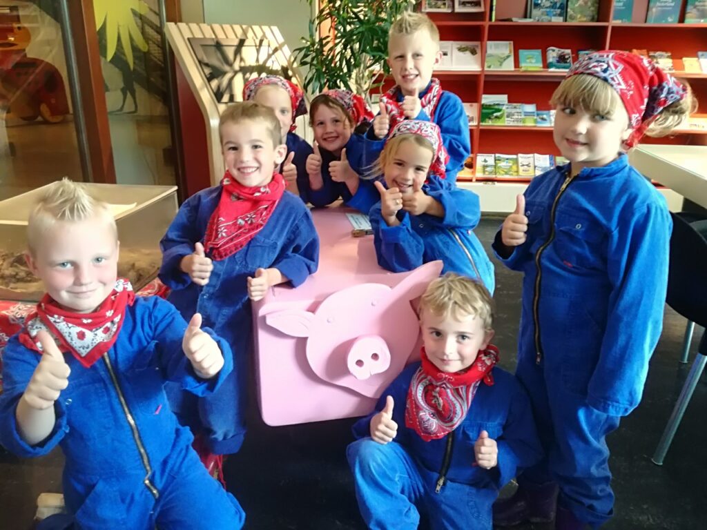 Groep kinderen in overalls steken hun duim op
