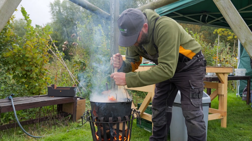 Tuinder maakt soep op open vuur tijdens het herfstfeest.